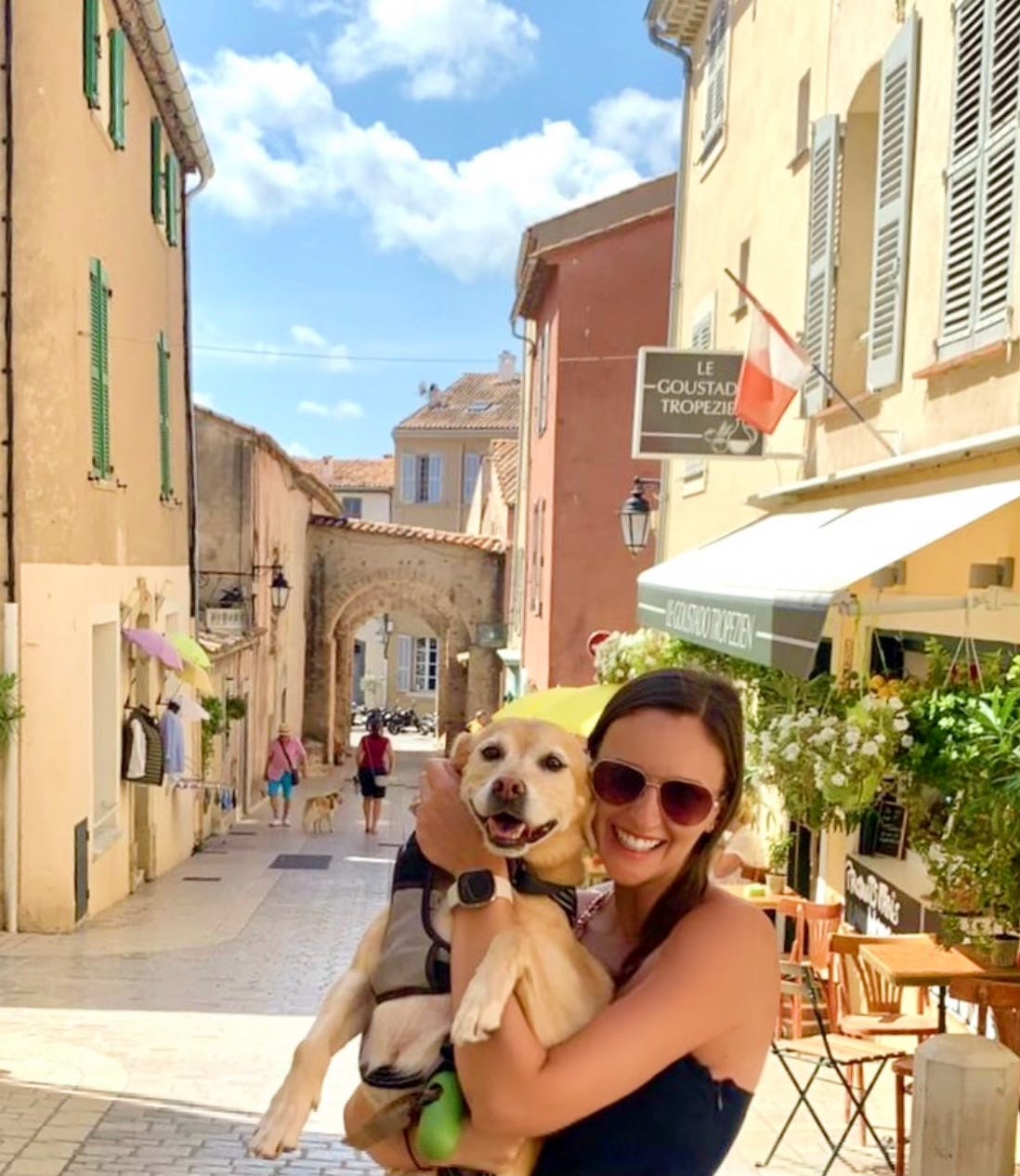 woman holding a dog on a street in St. Tropez