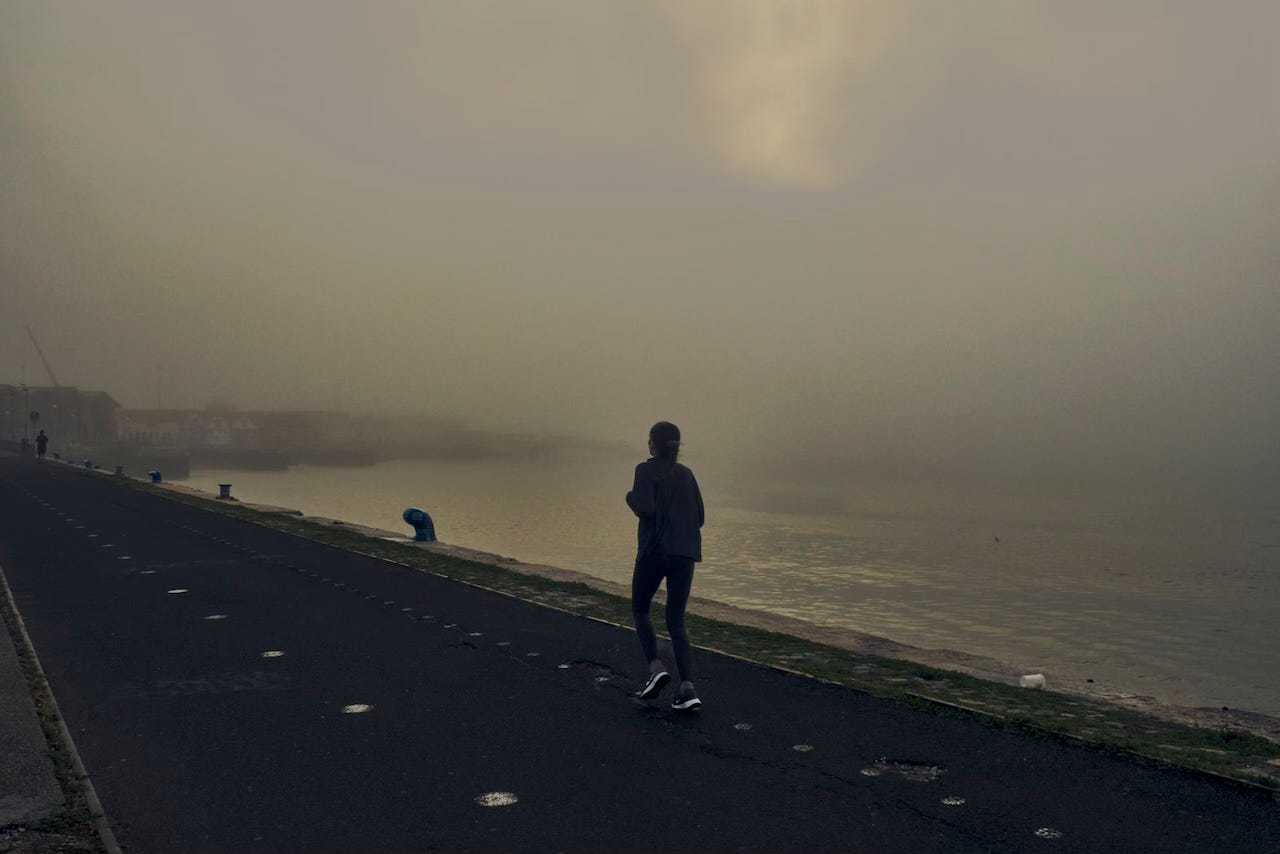 The silhouette of a runner against the foggy horizon on Lisbon's riverside The silhouette of a runner against the foggy horizon on Lisbon's riverside