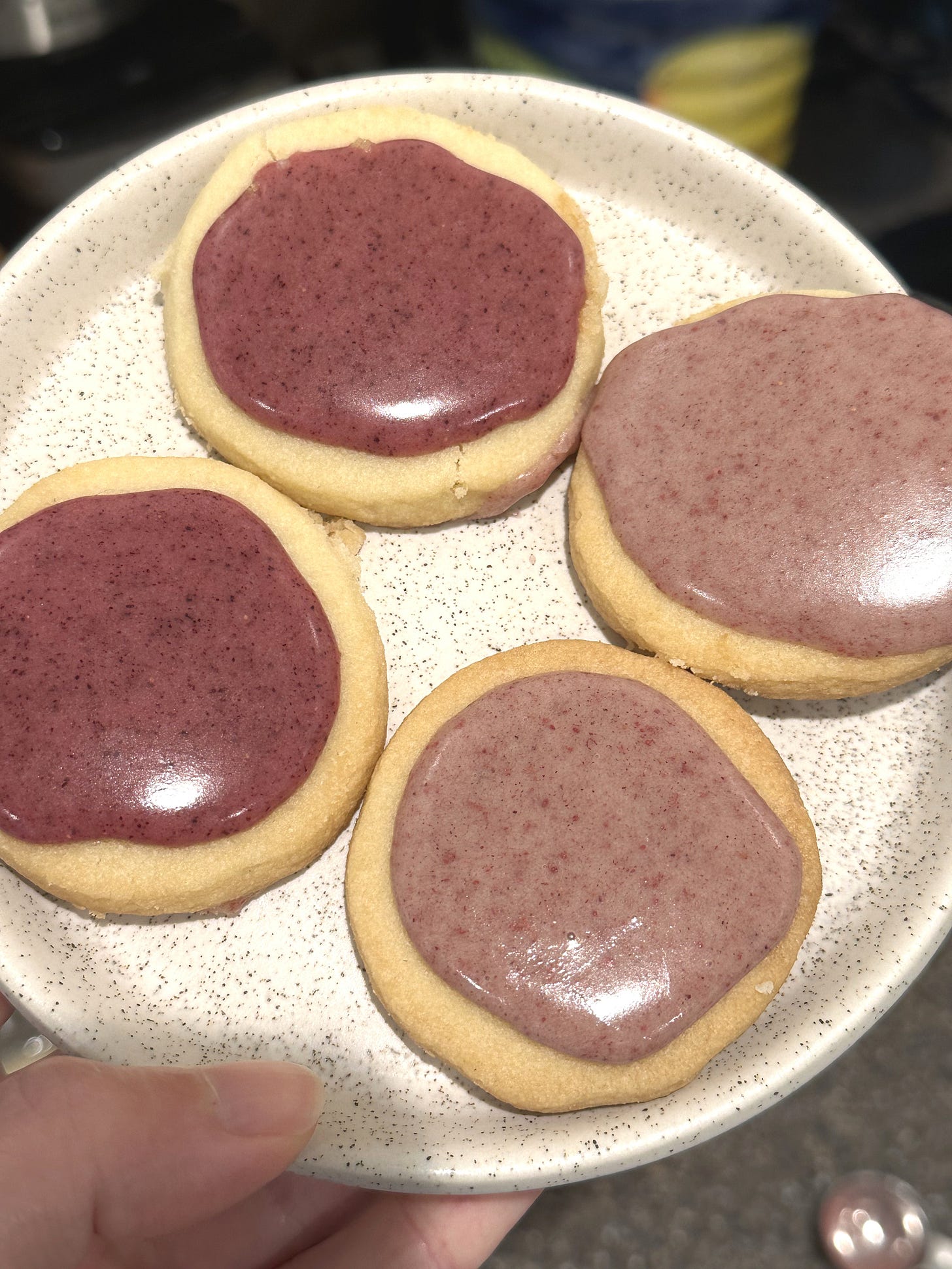 Hand holding plate of iced shortbread cookies