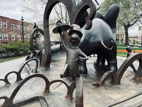 scupltures, signs, sidewalk, sky, grass, trees