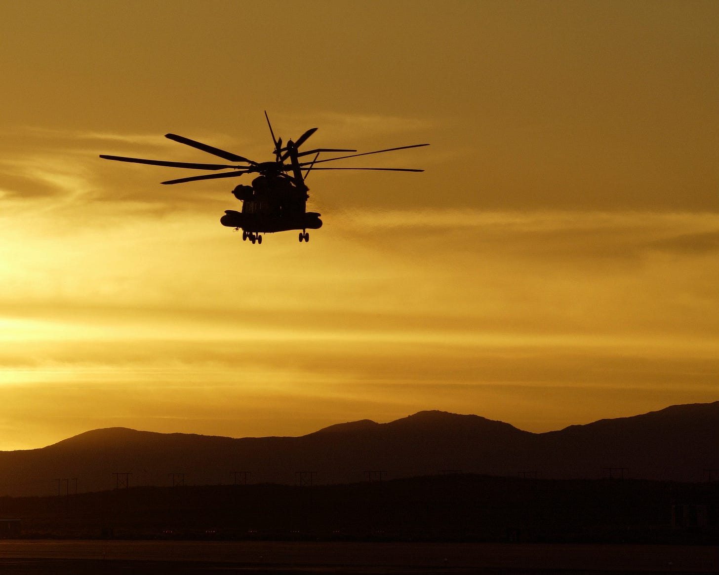 Marine helicopter flying into a desert sunset