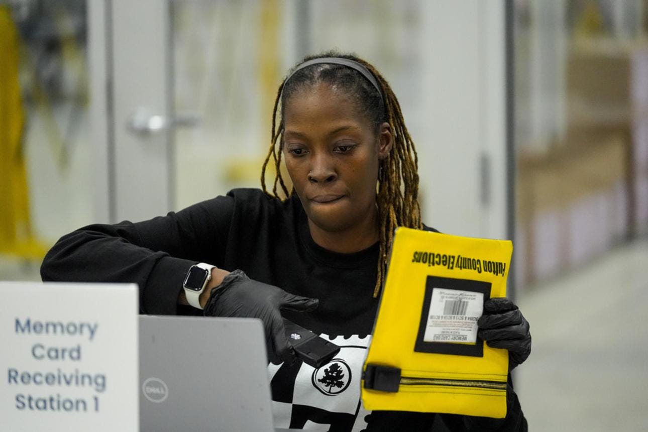 Election worker at the Fulton County operations center processing a yellow envelope containing a voting-equipment memory card. Election worker at the Fulton County operations center processing a yellow envelope containing a voting-equipment memory card.