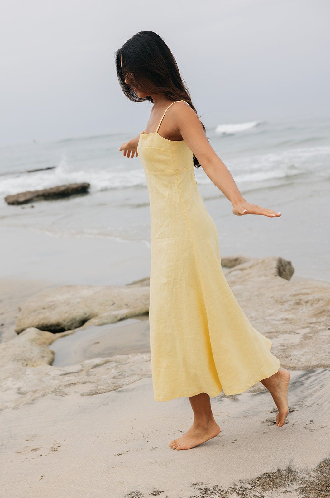Women having fun and playing on the beach in a yellow linen maxi dress Women having fun and playing on the beach in a yellow linen maxi dress