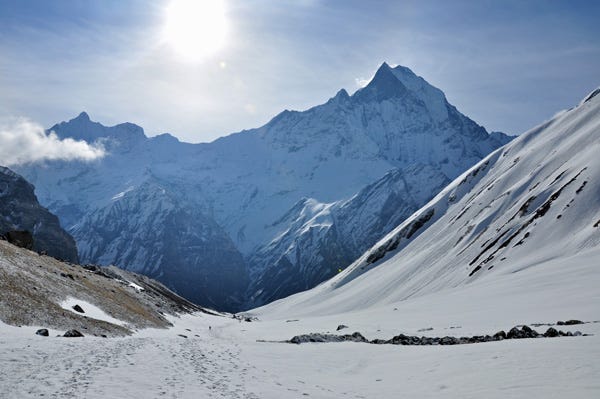 Snow-covered hiking trail with towering mountains in the background. Snow-covered hiking trail with towering mountains in the background.