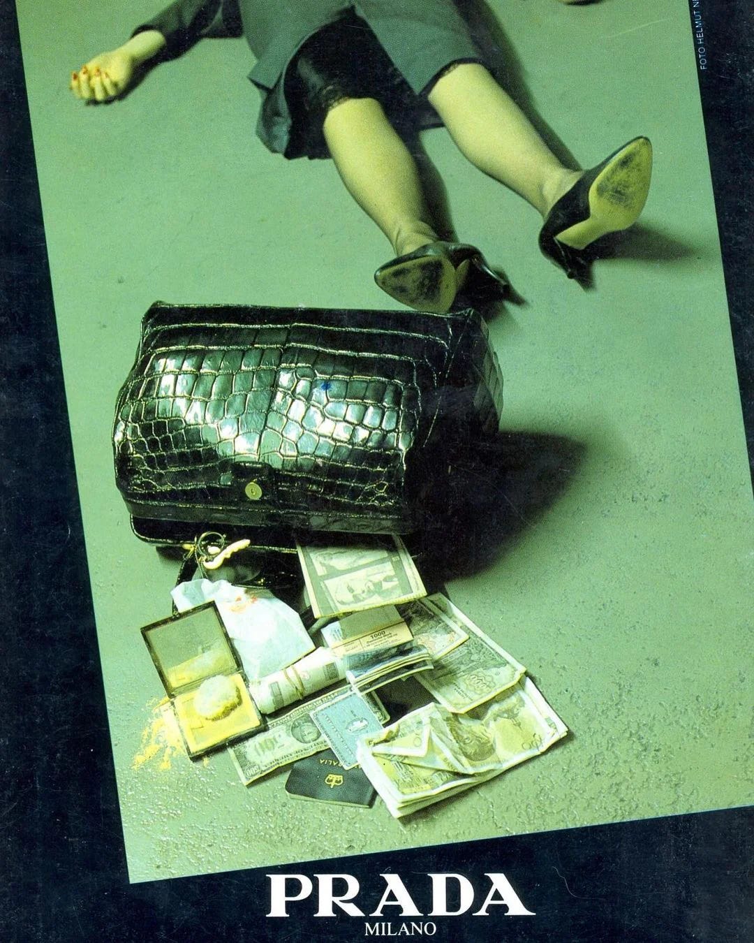 A green tinted image depicts an alligator handbgad fallen open with cash and keys and makeup pouring out of it and a woman's legs wearing high heels on her feet.