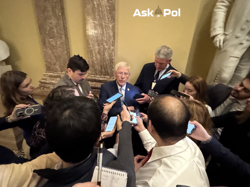 Politician in a suit and glasses is surrounded by journalists inside US Capitol. Photo Matt Laslo www.askapol.com 