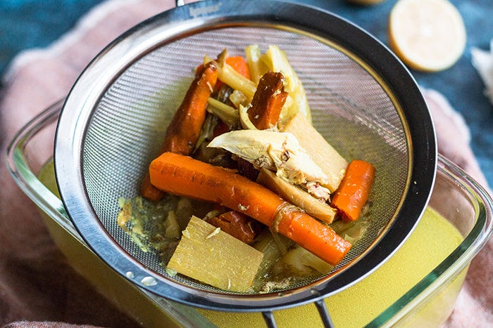 straining vegetables for ginger turmeric chicken soup