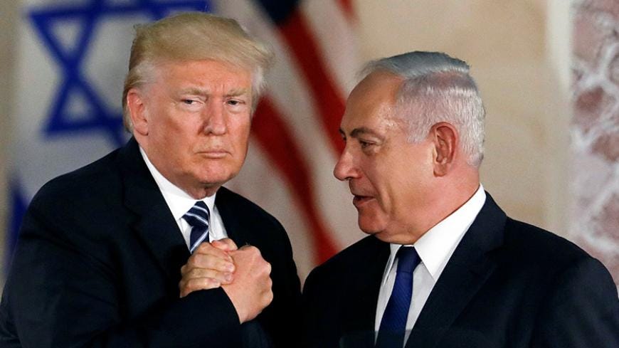 Trump and bib in a strong handshake in front of the israeli and american flags