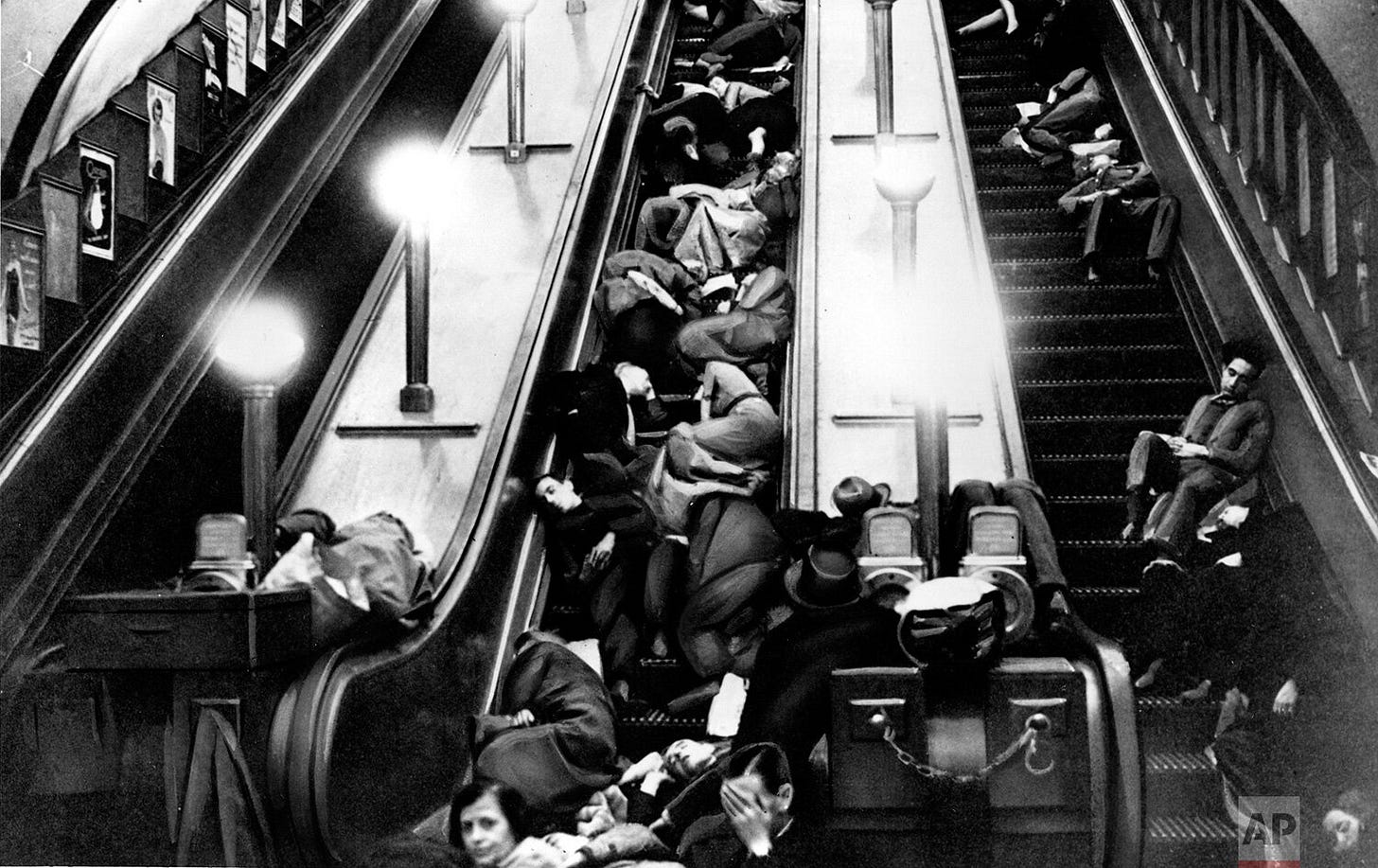 Seeking refuge from relentless German bombing, Londoners find makeshift beds on the halted escalators of a tube station, transforming it into a communal air-raid shelter during the 1940 Blitz. Seeking refuge from relentless German bombing, Londoners find makeshift beds on the halted escalators of a tube station, transforming it into a communal air-raid shelter during the 1940 Blitz.