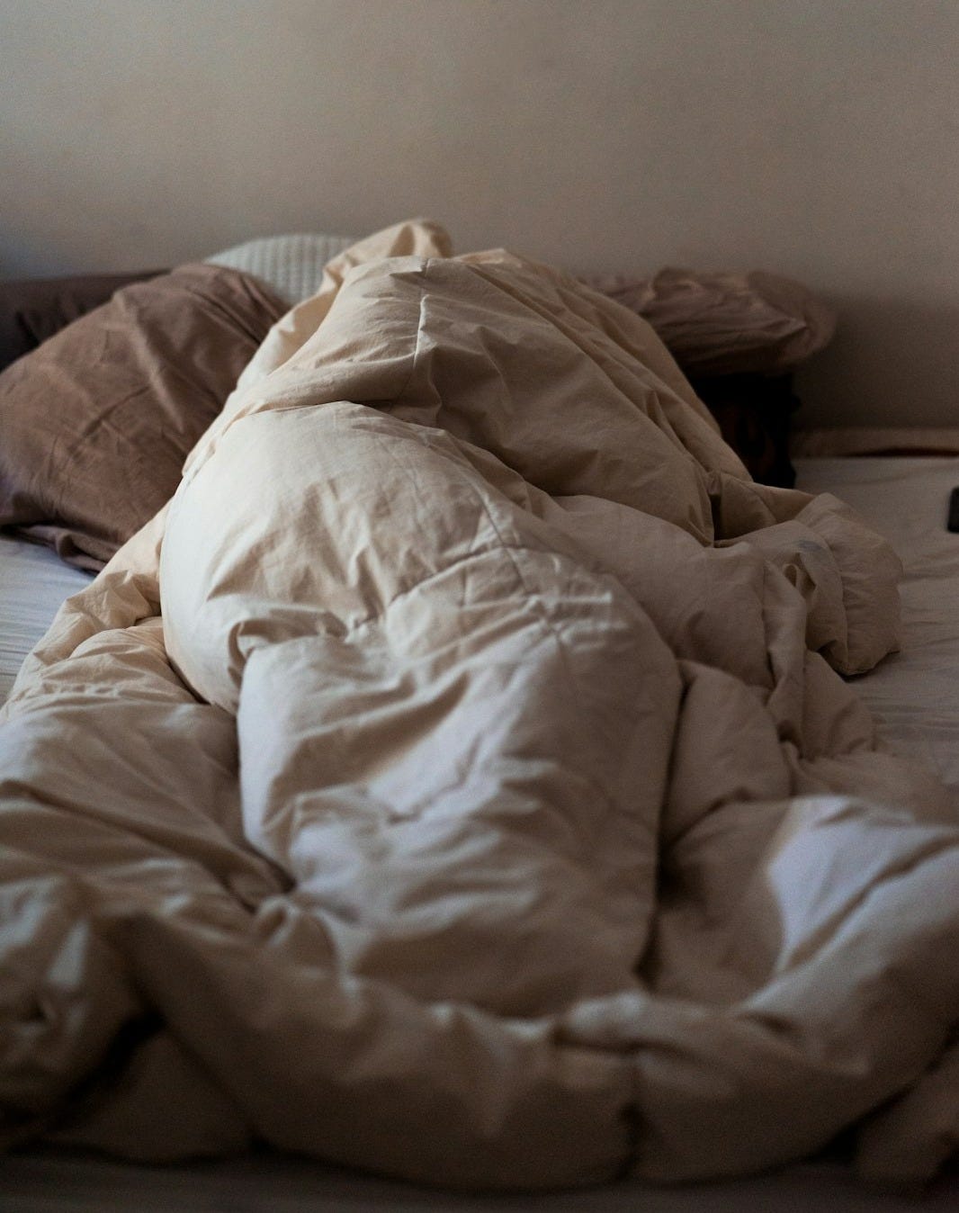 an unmade bed with a white comforter on top of it