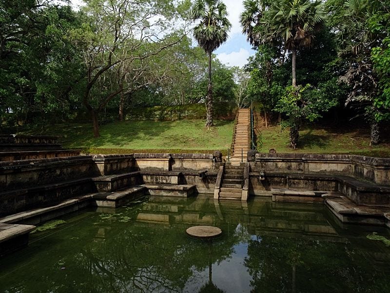 Ancient stone pool with steps and surrounding ruins