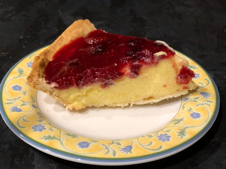 A bowl of strawberries, pastry on floor, a fruit flan