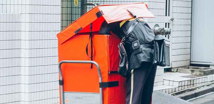 Photo of a postal worker reaching into a large container.