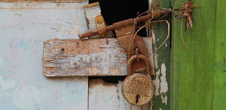 Photo of an old padlock on a rotting wooden door