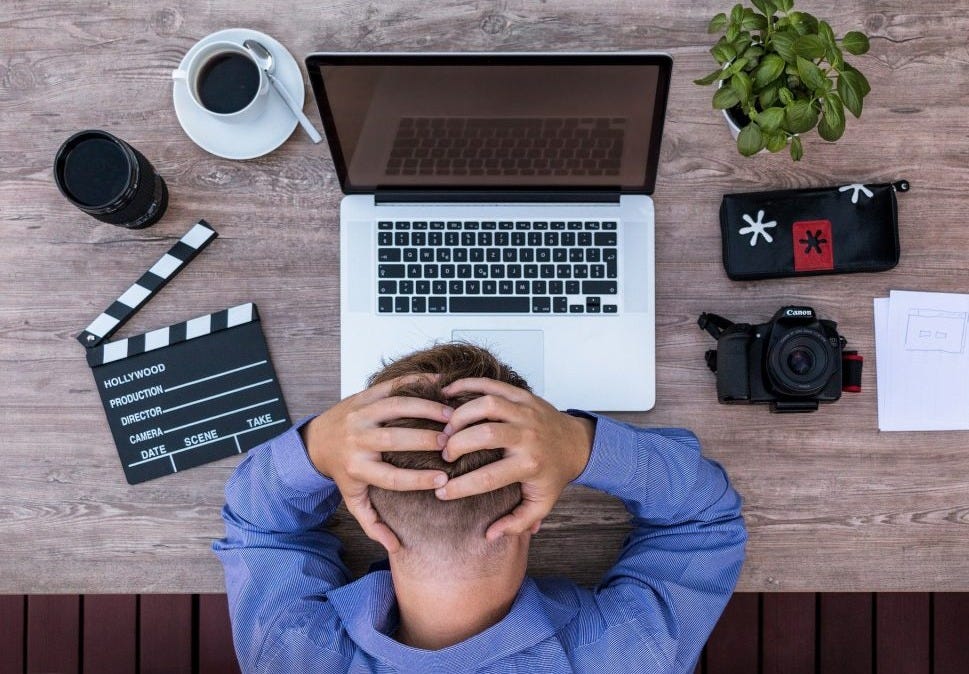 Man grabbing his head in front of a computer from frustration fro writer burnout Man grabbing his head in front of a computer from frustration fro writer burnout