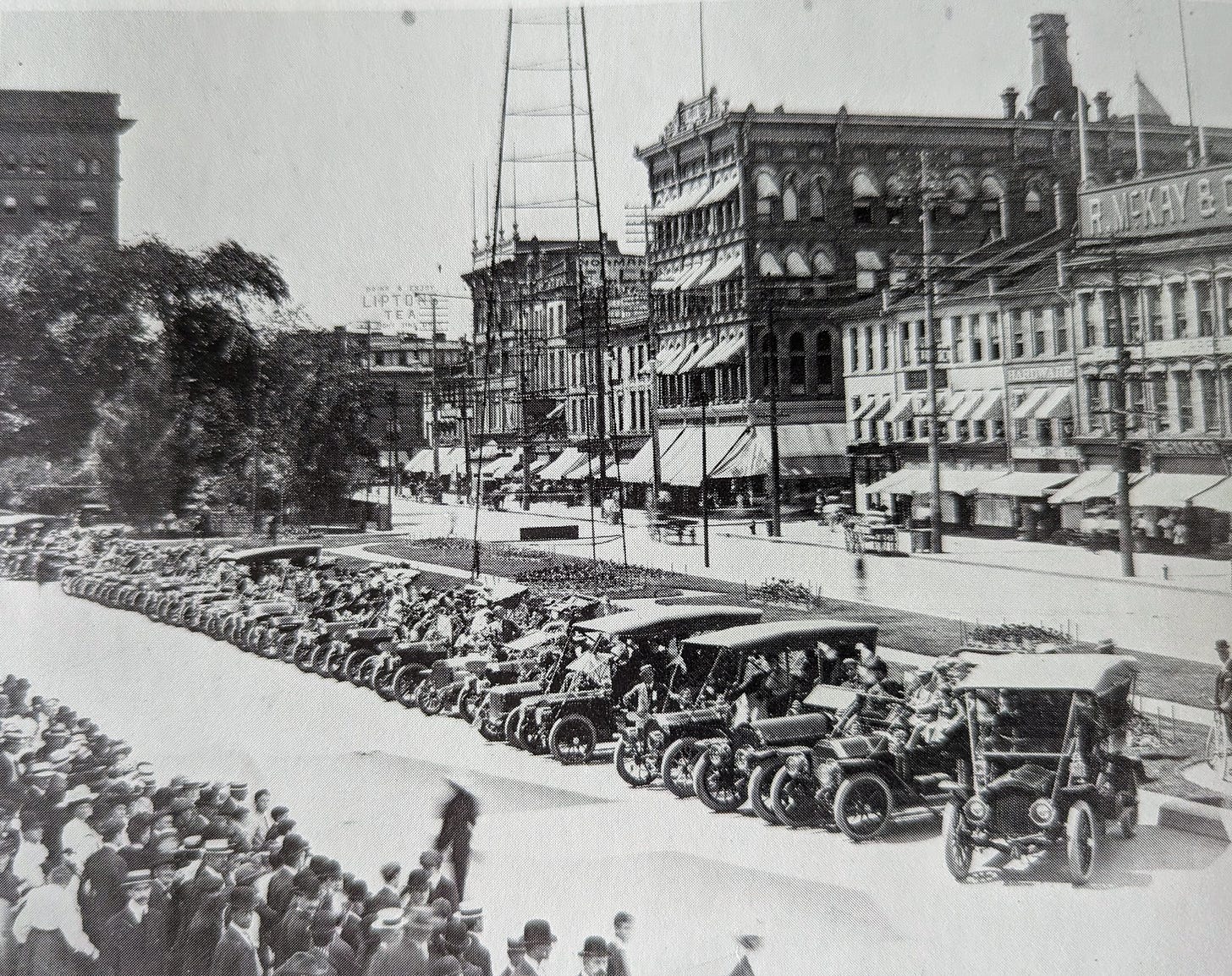 A line of cars from the early 1900s in front of Hamilton's Gore Park with lines of spectators looking at the vehicles. A line of cars from the early 1900s in front of Hamilton's Gore Park with lines of spectators looking at the vehicles.