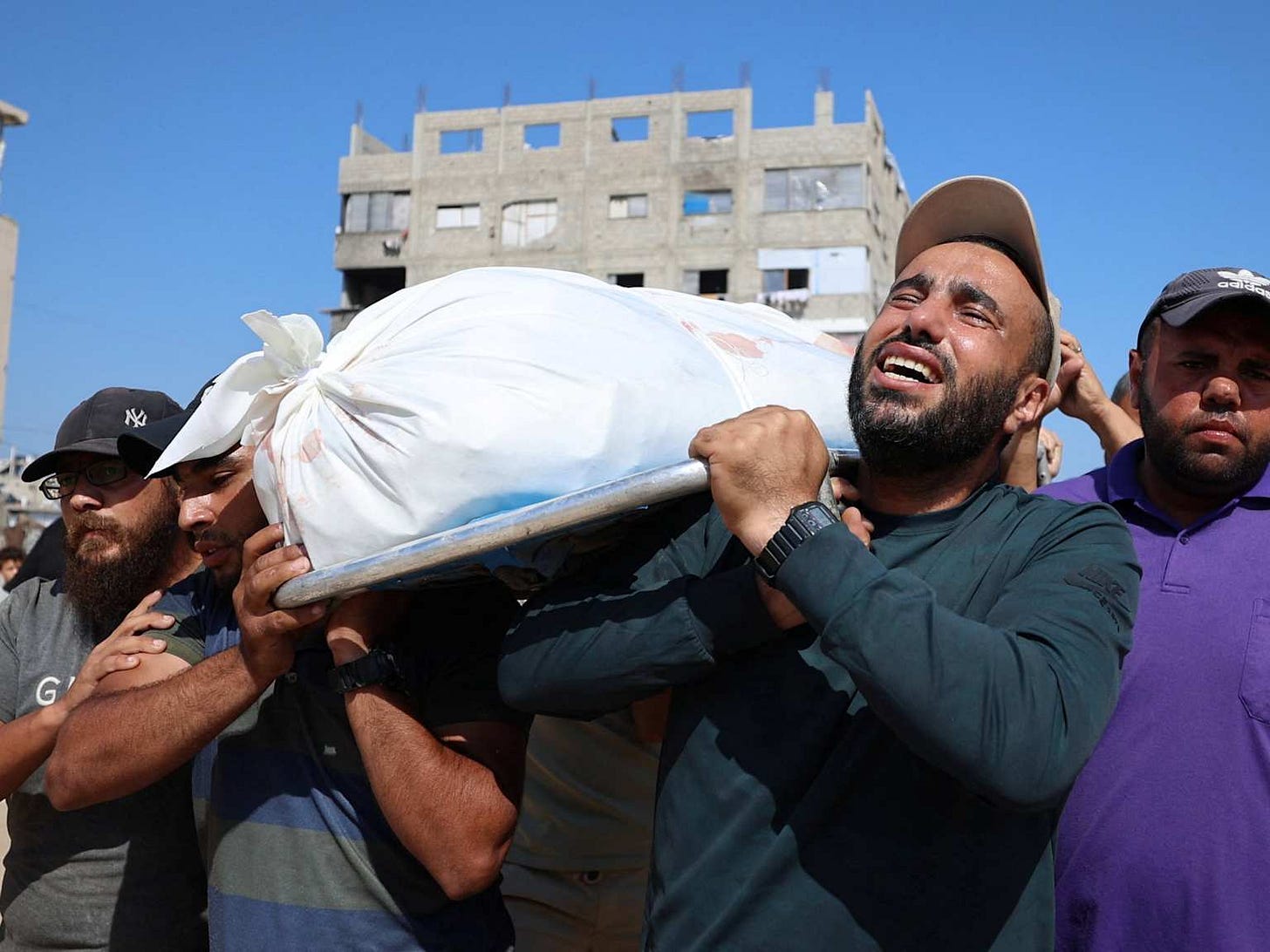 Palestinians carry a shrouded body through the ruins of a Gaza neighborhood during the ceasefire period