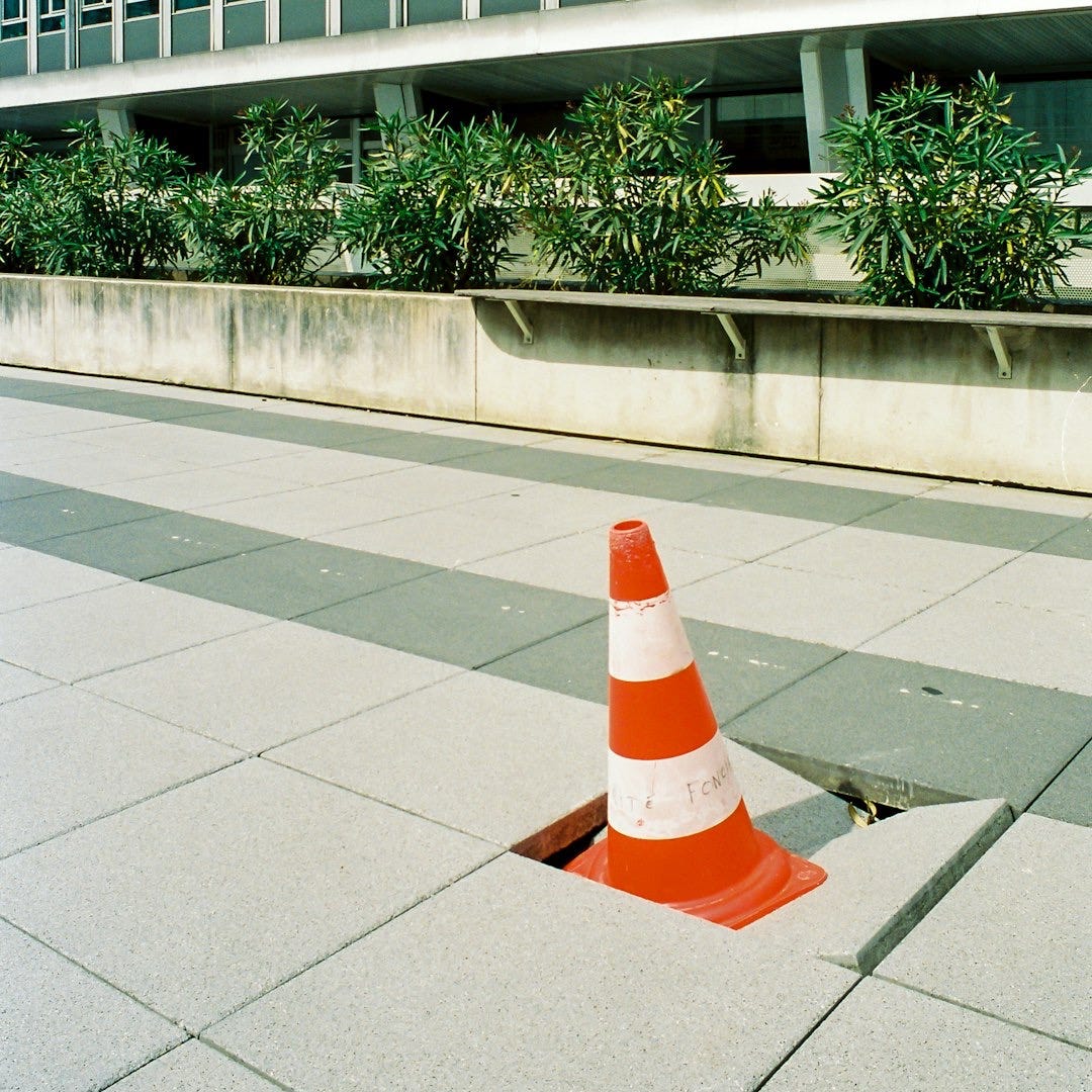 orange and white traffic cone on gray concrete floor
