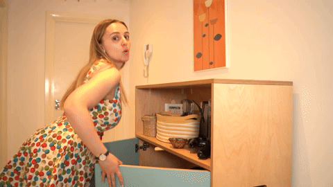 Hannah exaggeratedly closing a cupboard with her hips like a pin-up girl