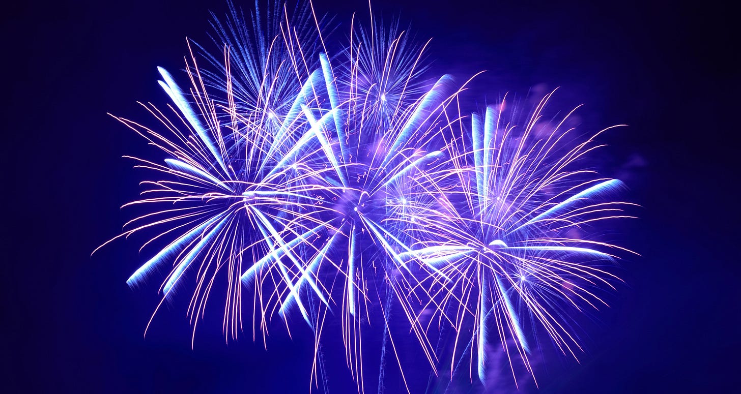 Purple fireworks bursting against a midnight blue sky