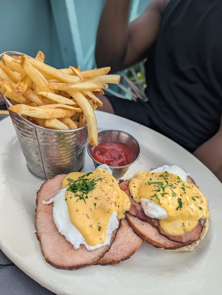 Left to right: Crispy fish tacos covered with purple cabbage slaw, red onions, and cilantro with a salsa verde on the side; Eggs Benedict with ham covered in hollandaise served with a side of fries.