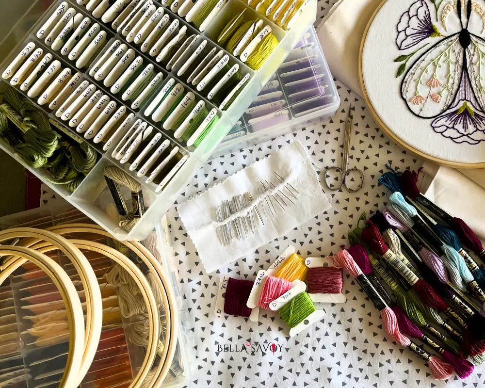 bird's eye view of hand embroidery supplies: hoops, thread, fabric, organizer, cards, scissors, needles