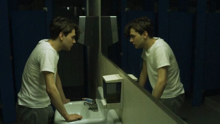 This may contain: two young men standing in front of a mirror looking at each other's reflection