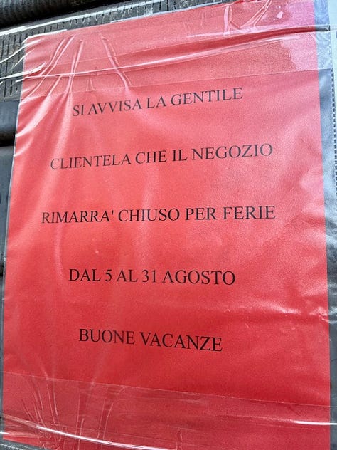 Chiuso per ferie, handwritten signs saying the shops are closed for the month of August and overgrown plants on the sidewalk