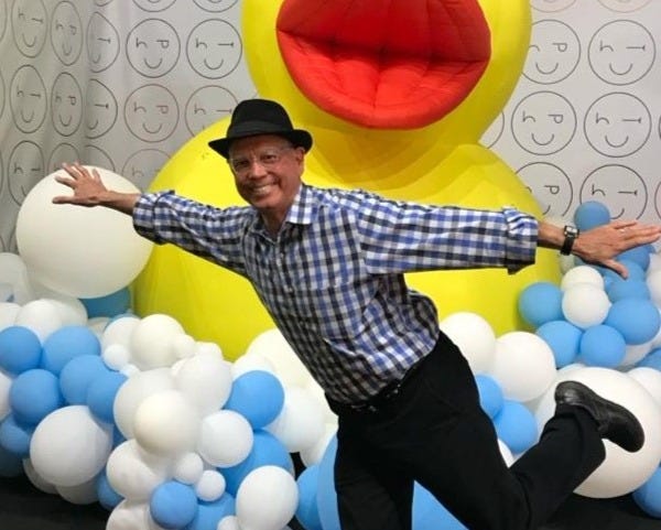 A person standing in front of a yellow duck balloon

Description automatically generated
