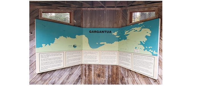The first photo shows a new, brightly colored Batchewana First Nation sign.  The sign looks relatively new and stands in stark visual contrast to the older park sign. Blurry trees and a hint of the gravel path are visible in the background.  The second photo shows  a weathered, brown Ontario Parks sign at the Gargantua trailhead. The sign looks worn.