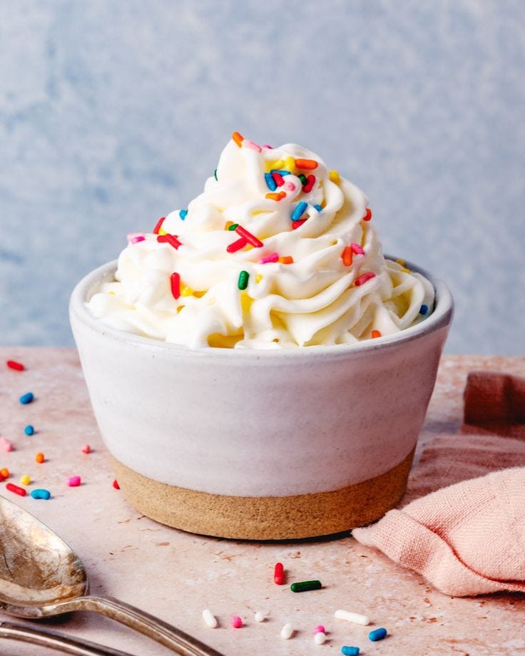 This may contain: a white bowl filled with whipped cream and sprinkles