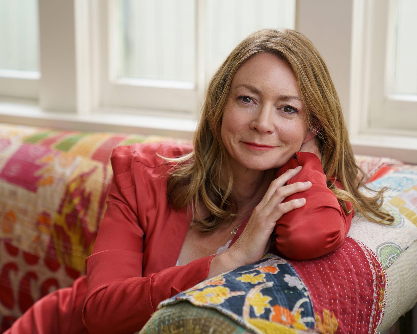 amanda mccracken, author of when longing becomes your lover, smiling on couch amanda mccracken, author of when longing becomes your lover, smiling on couch