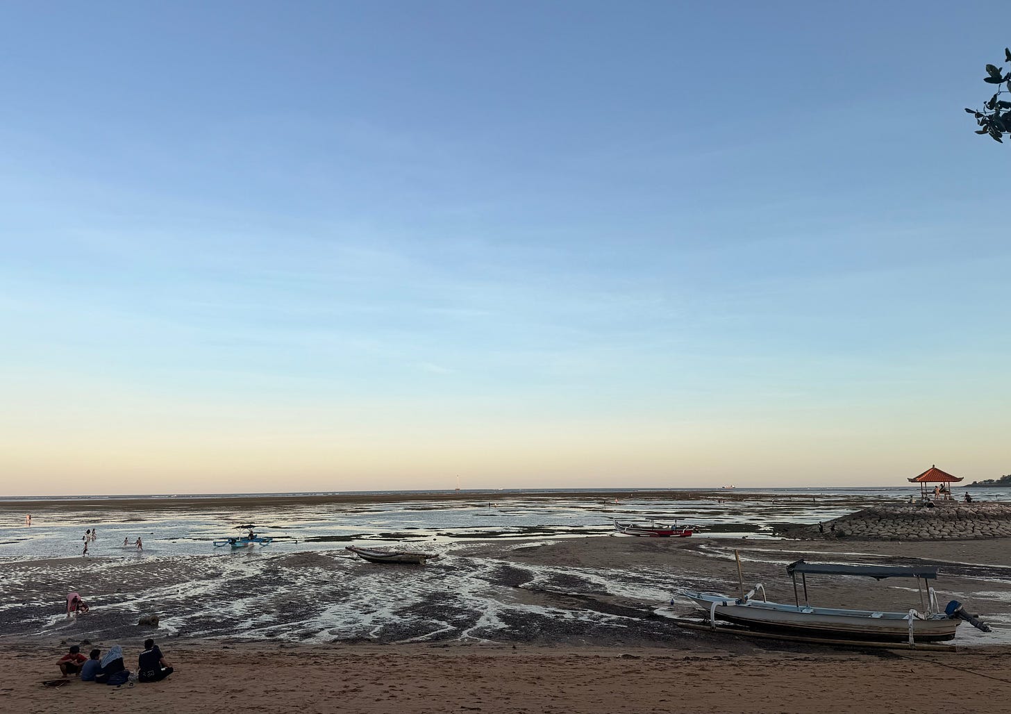 Calm ocean water at sunset in Bali with soft light and minimal activity along the shore.