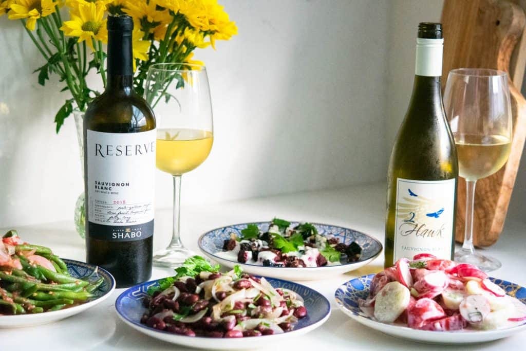 4 round plates with Ukrainian salads and 2 bottles of sauvignon blanc white wine 4 round plates with Ukrainian salads and 2 bottles of sauvignon blanc white wine