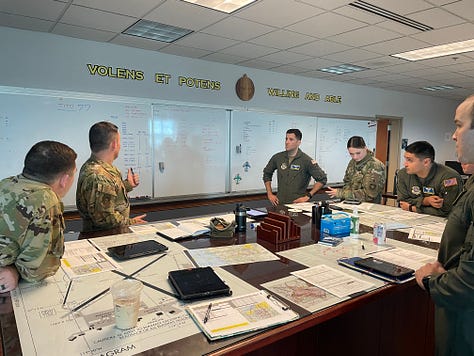 A crew mission planning, an empty cargo bay with mist and the American flag, the back of a C-17 with Presidential vehicles loaded