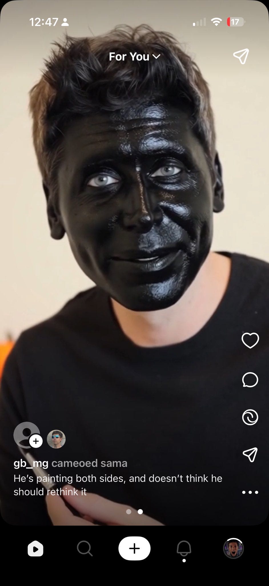 A person with short, dark hair wearing a black shirt, their face covered in shiny black paint, creating a striking, uniform appearance. A TikTok watermark is visible at the bottom right corner.