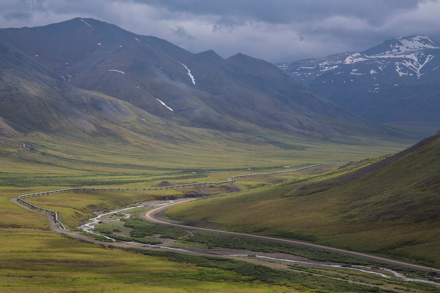 The Dalton Highway, which parallels the, Trans Alaska Pipeline, is seen on July 3, 2014, just north of Coldfoot, a community 60 miles north of the Arctic Circle. In view next to the highway is the middle fork of the Koyukuk River, and looming in the background are mountains in the Brooks Range. The Dalton Highway is the only road leading from the established highway network to the North Slope, and it is a vital supply route for North Slope oil operations. (Photo by Bob Wick/Bureau of Land Management) The Dalton Highway, which parallels the, Trans Alaska Pipeline, is seen on July 3, 2014, just north of Coldfoot, a community 60 miles north of the Arctic Circle. In view next to the highway is the middle fork of the Koyukuk River, and looming in the background are mountains in the Brooks Range. The Dalton Highway is the only road leading from the established highway network to the North Slope, and it is a vital supply route for North Slope oil operations. (Photo by Bob Wick/Bureau of Land Management)