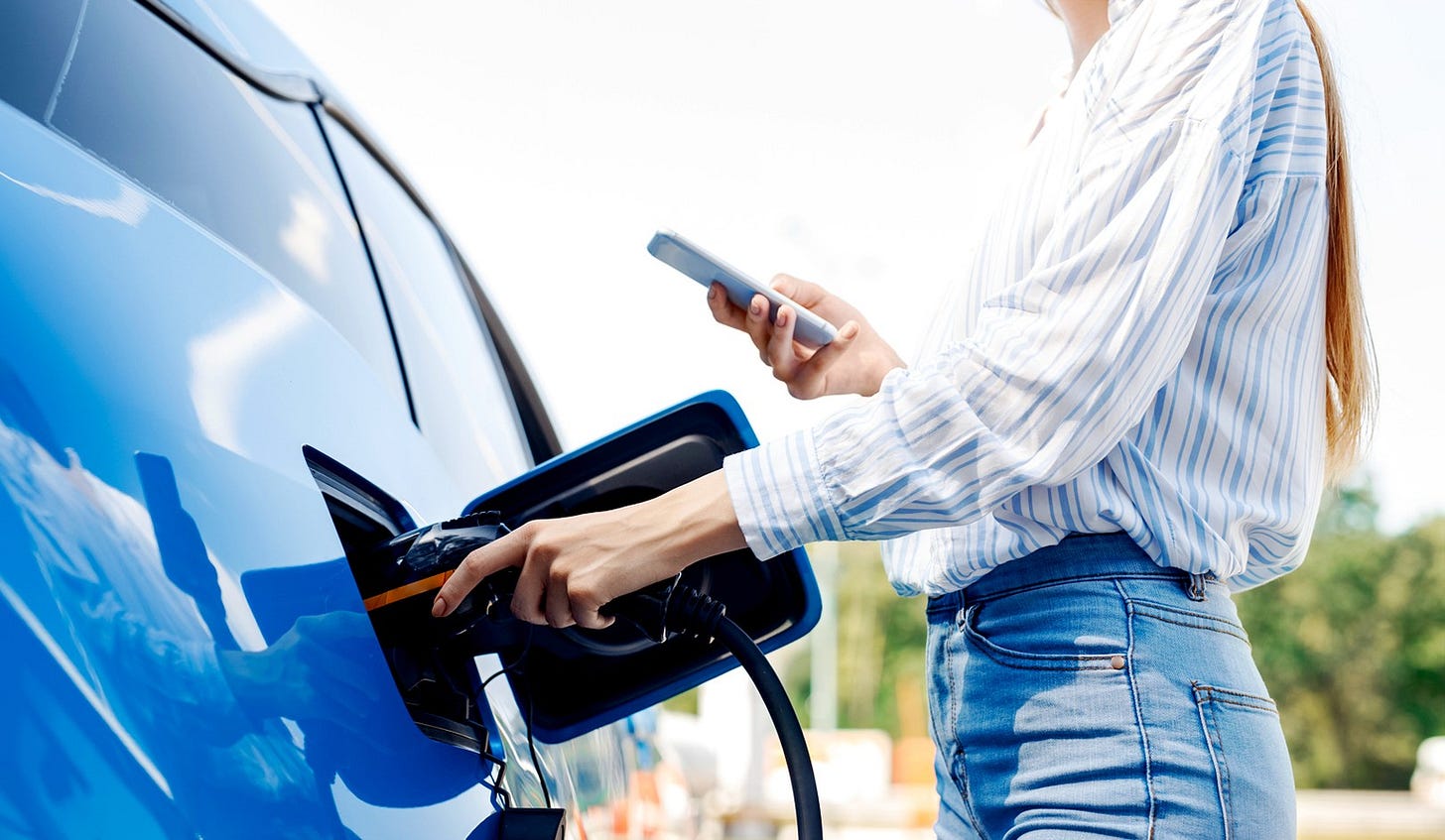 A woman charging her blue EV outside. A woman charging her blue EV outside.