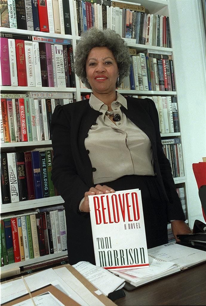 Pinterest image of Toni Morrison posing with a first edition copy of her novel Beloved from 1987