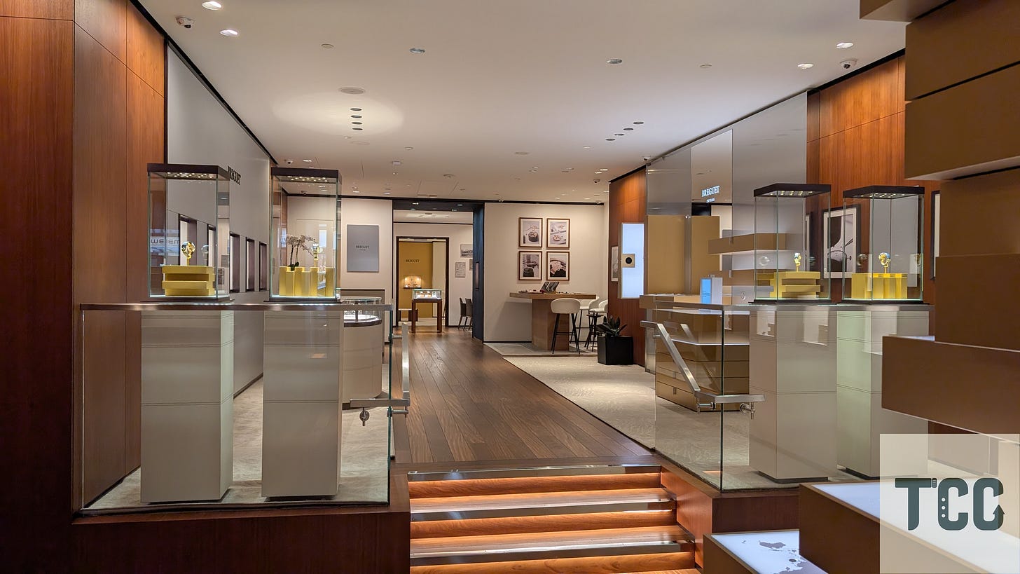 Interior view of Breguet boutique entrance with watch display cases on both sides, wood paneling, and a softly lit showroom.