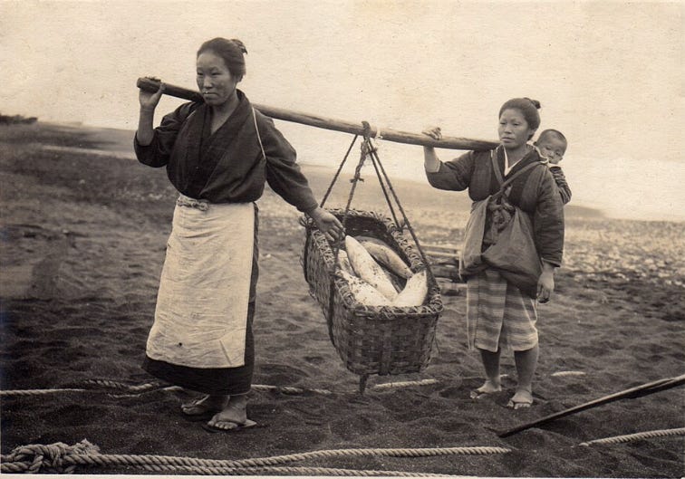 Two Japanese women carrying a basket of fish - Bringing in the Catch - 1915 by Elstner Hilton
