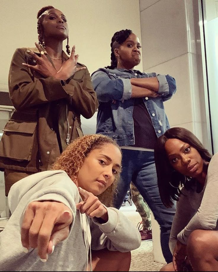 This may contain: four people standing in front of a mirror with their arms crossed and pointing at the camera