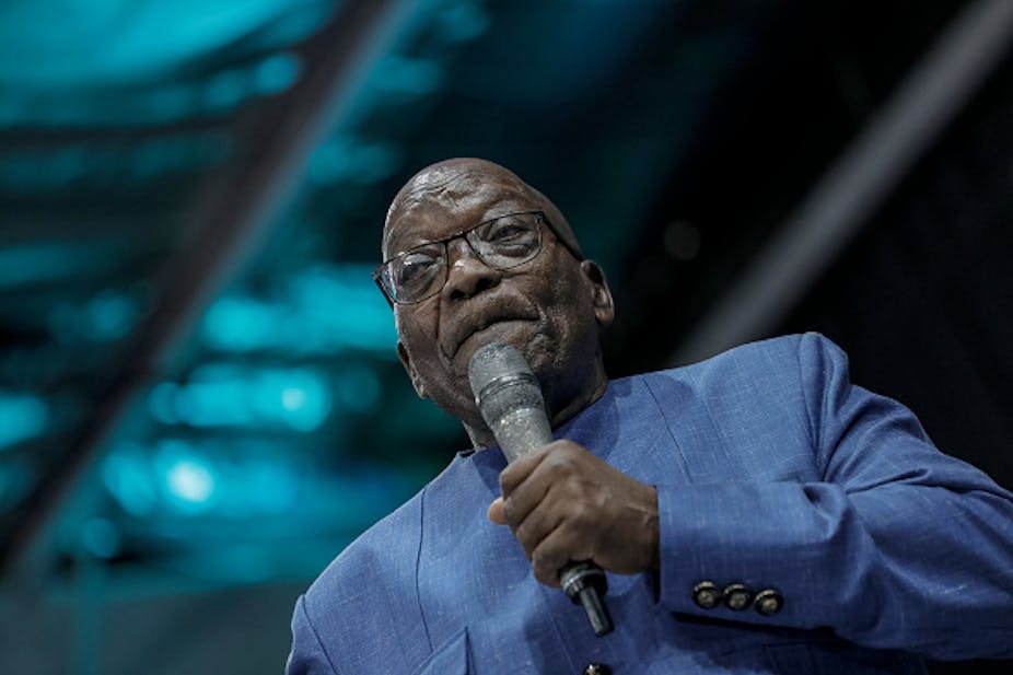 A man speak into a microphone in his left hand. A man speak into a microphone in his left hand.