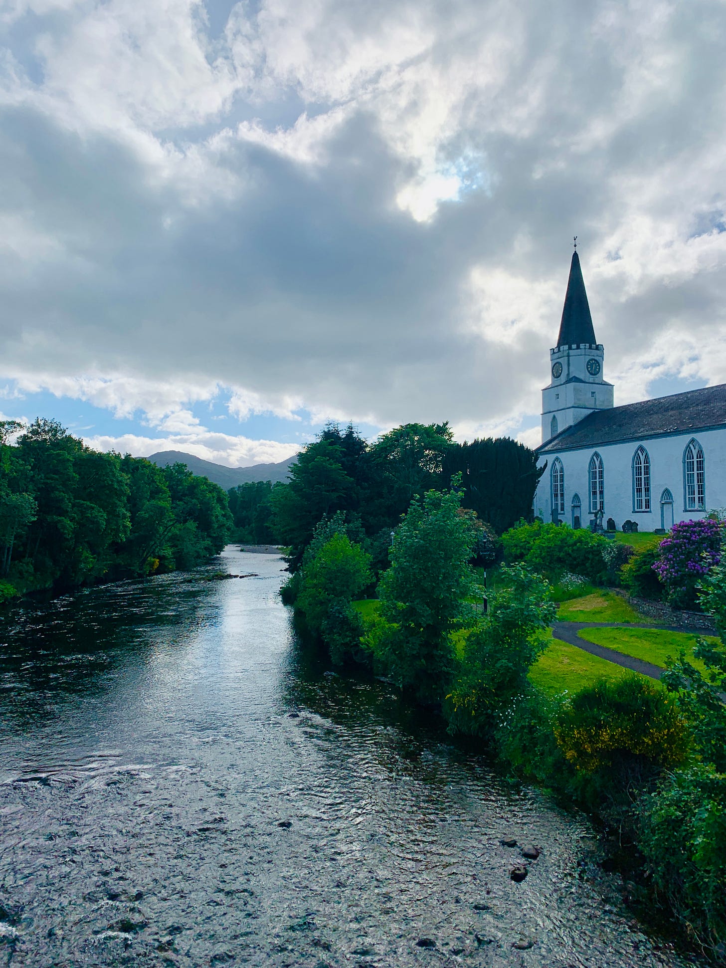 A river flowing beside a white church and old graveyard