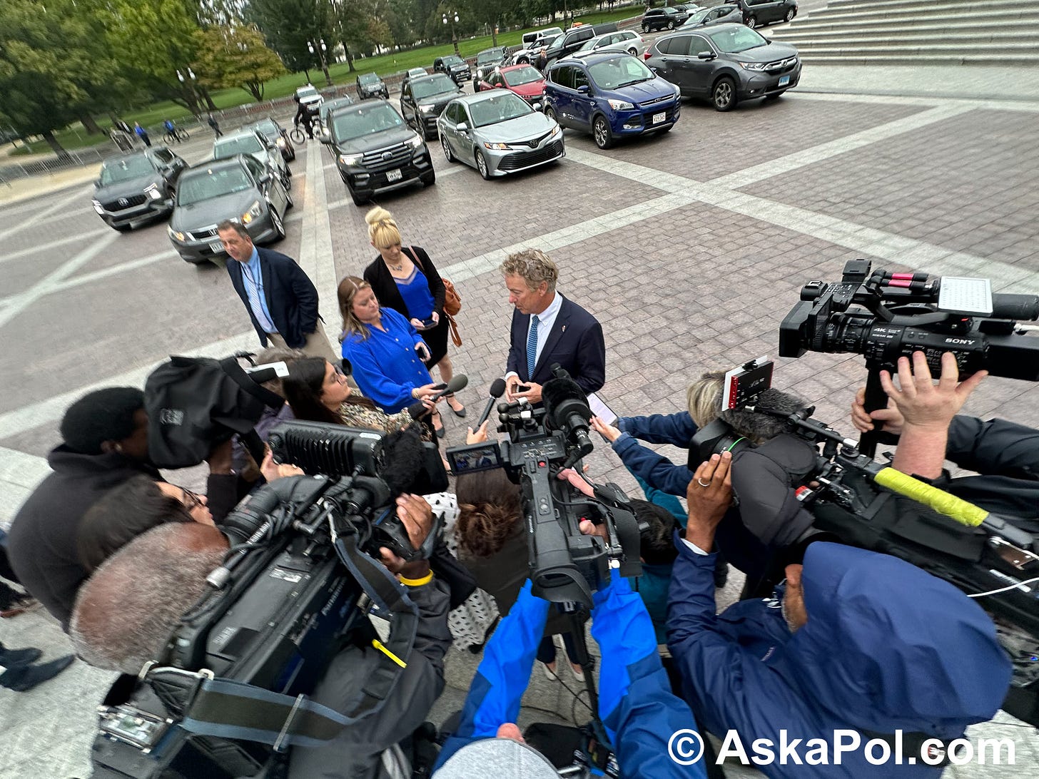 A man in a suit addresses television cameras. Photo: MATT LASLO © Ask a Pol Drugs