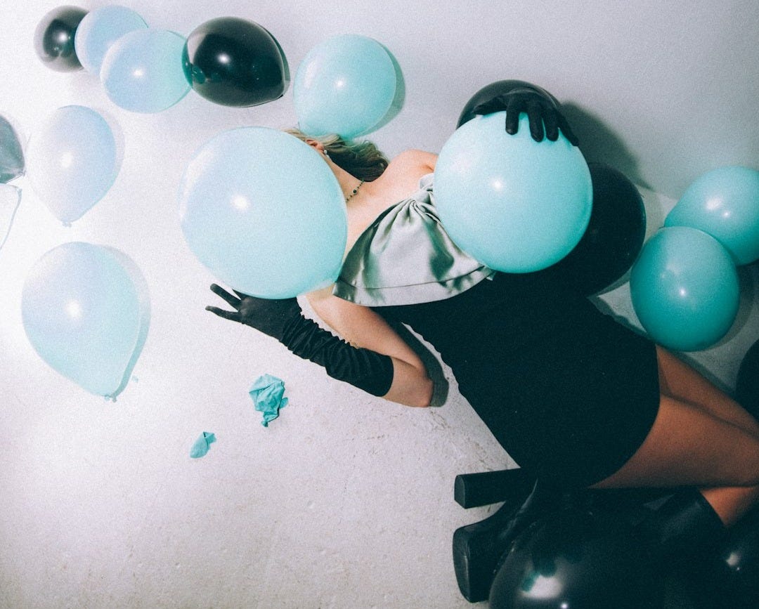 a woman in a black dress is surrounded by balloons a woman in a black dress is surrounded by balloons
