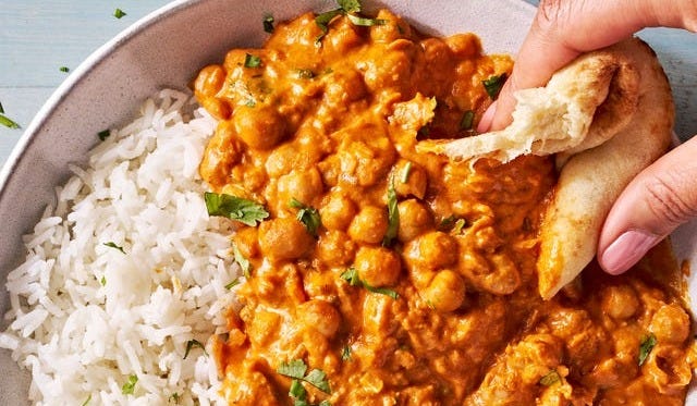 indian butter chickpeas and rice in a bowl with pita