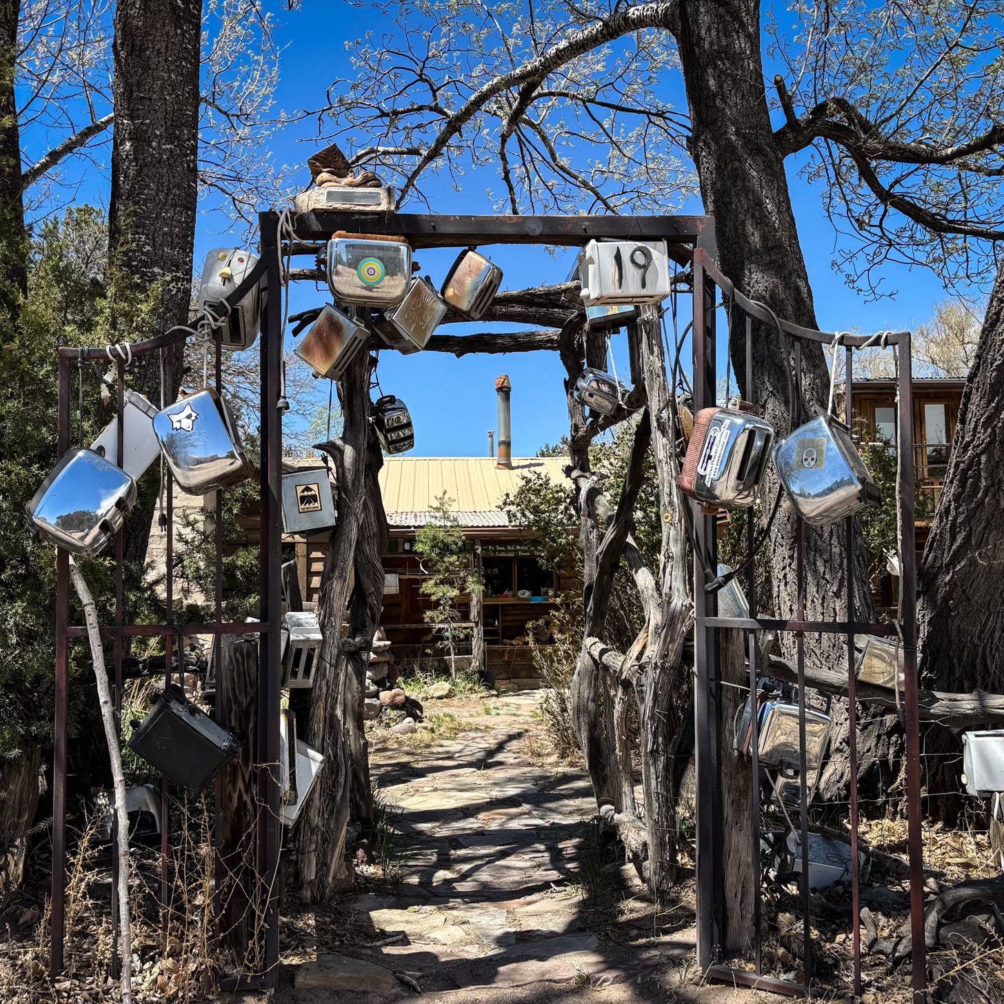 Toasters hanging off of metal gate in front of rustic house