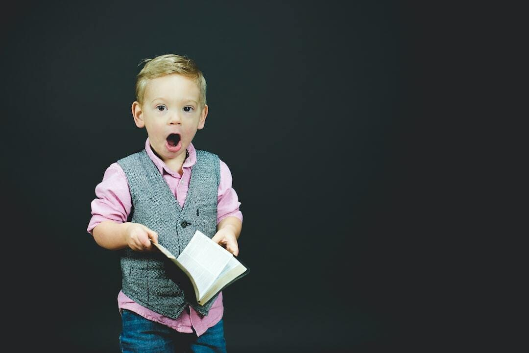 boy wearing gray vest and pink dress shirt holding book boy wearing gray vest and pink dress shirt holding book