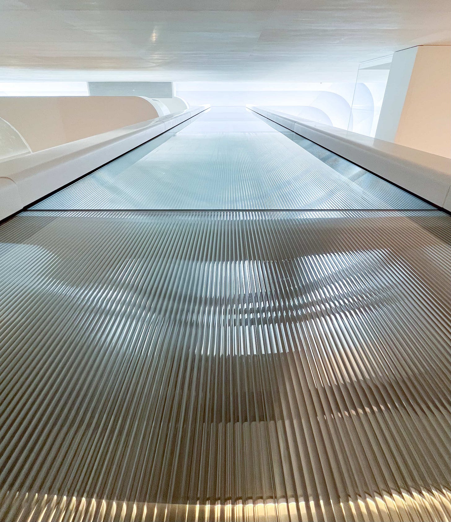 Fluted glass on the elevator shaft at Apple The Exchange TRX. The camera is pointing toward the ceiling from the lowest level of the store.